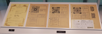 （写真）QRコードの特許証と試作当時のデザイン画