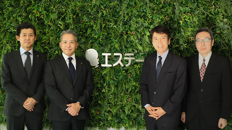 （写真）エステー株式会社との意見交換　前田コア事業本部担当兼R&D本部担当 執行役（左）、上月代表執行役社長（中央左）、河西長官（中央右）、吉澤総務部長（右）